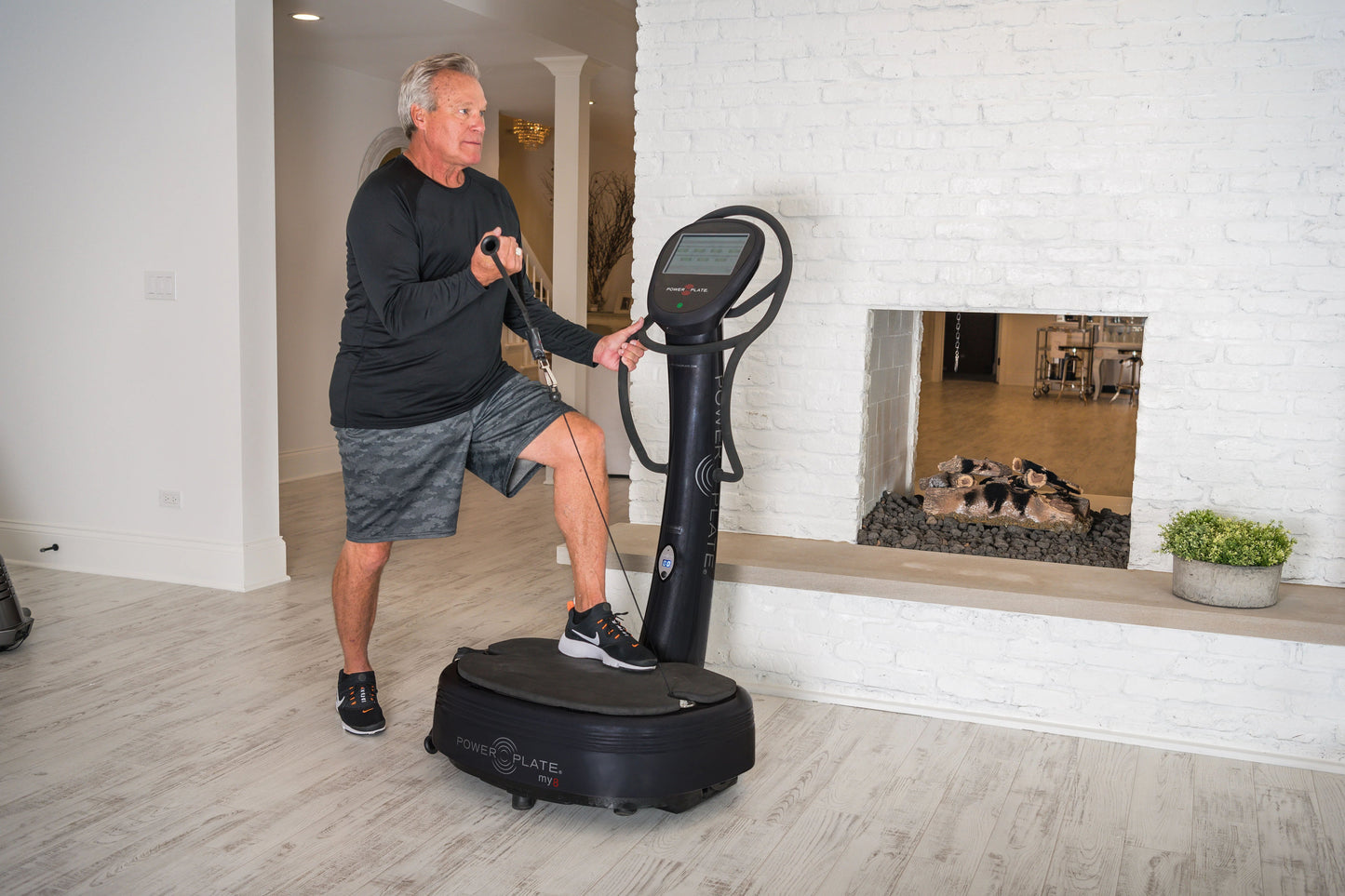 Man exercising on black Power Plate My8 vibration plate trainer with digital display in home gym setting