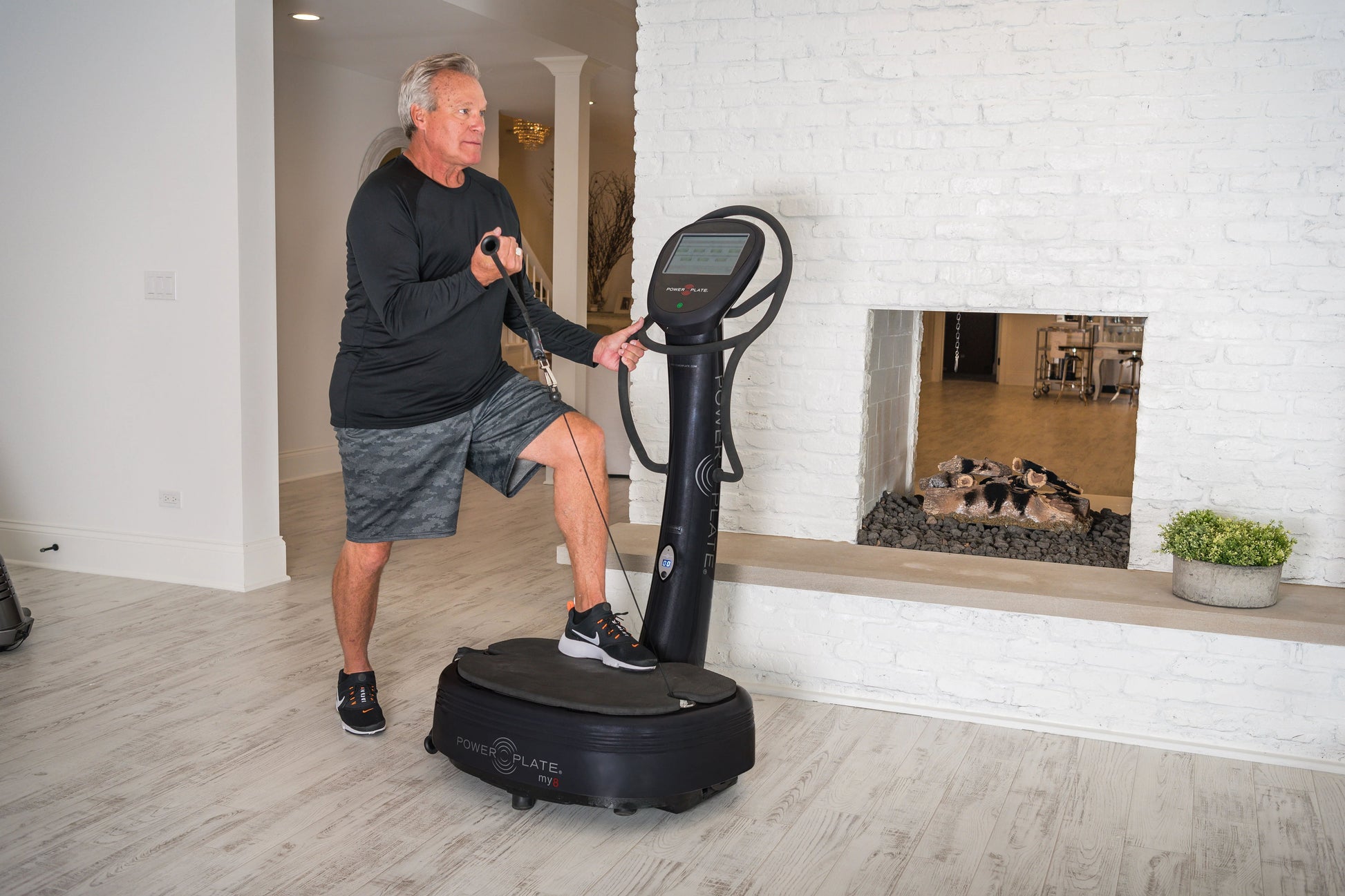 Man exercising on black Power Plate My8 vibration plate trainer with digital display in home gym setting