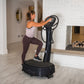 Woman in white tank top and burgundy leggings using black Power Plate My8 vibration trainer in modern gym setting