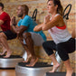 Group of people performing squats on vibration plates against brick wall during fitness class
