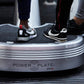 Two people wearing athletic sneakers standing on a Power Plate Pro5 vibration plate trainer with gray textured surface and wh