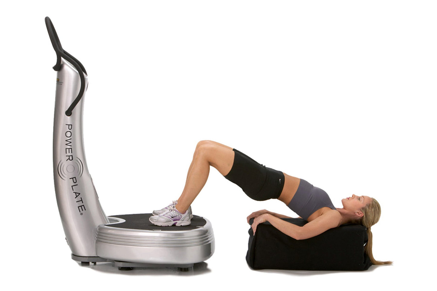 Silver Power Plate vibration platform with black handle bar, woman using machine in black and purple workout clothes on white