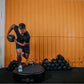 Man performing dynamic exercise on Power Plate Pro5HP vibration trainer, holding medicine ball mid-movement in gym setting wi