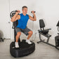Man in blue tank top using Power Plate Pro8 vibration trainer with resistance bands in home gym setting