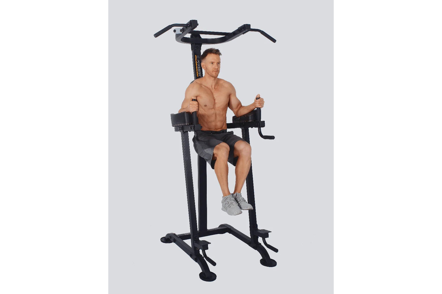 Black multi-function power tower with pull-up bar and leg raise station, demonstrated by shirtless male model on gray backgro