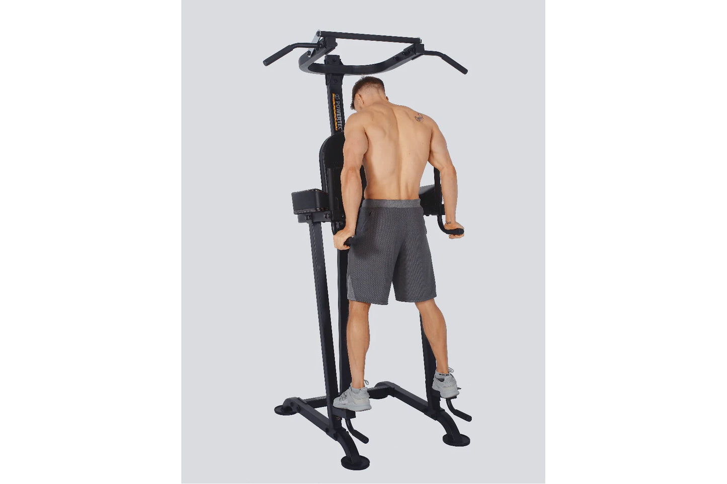 Black power tower with VKR station and pull-up bar, model demonstrating use in gray shorts on white background