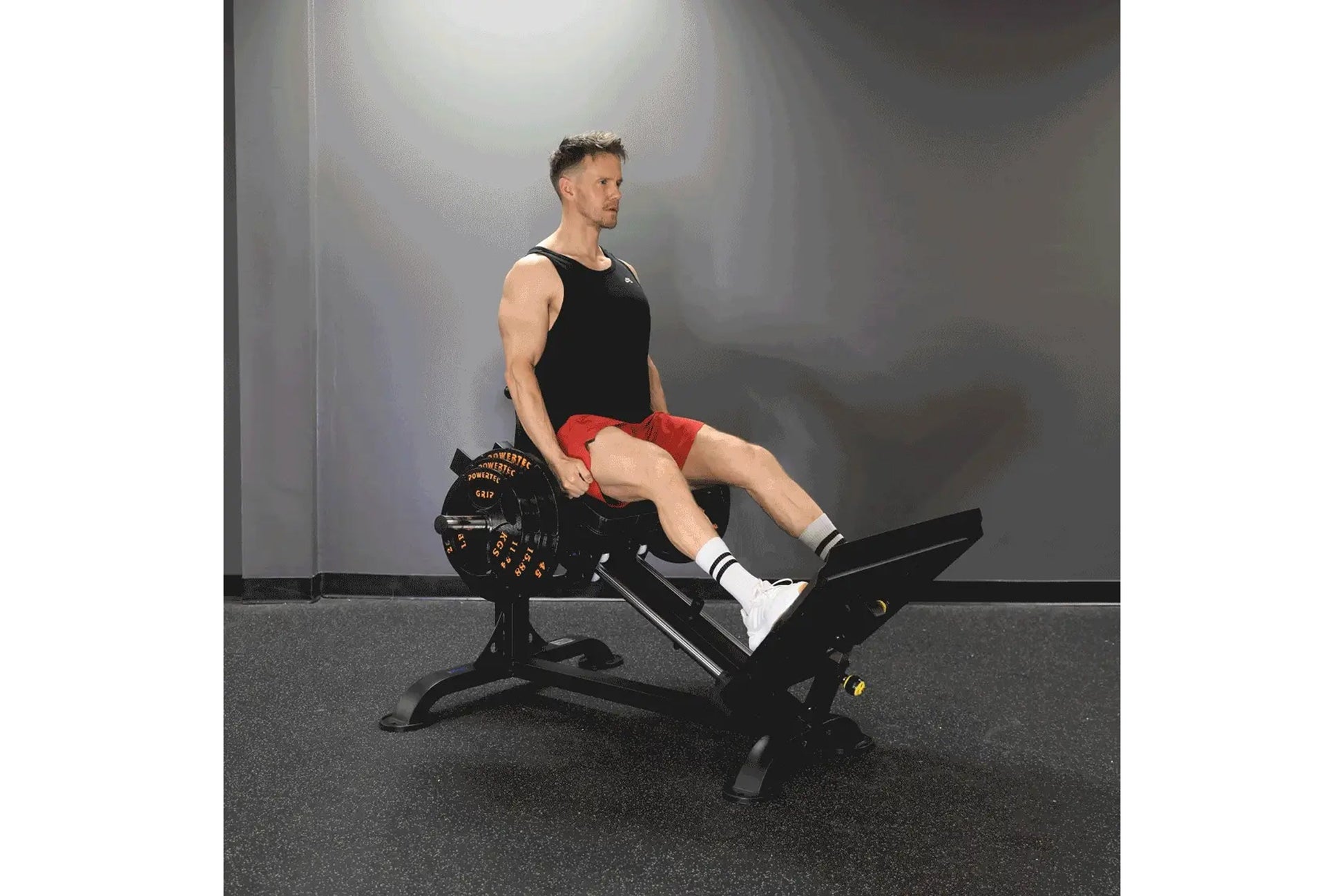 Black and red Powertec compact leg sled with plate storage, worn by male model in gym setting