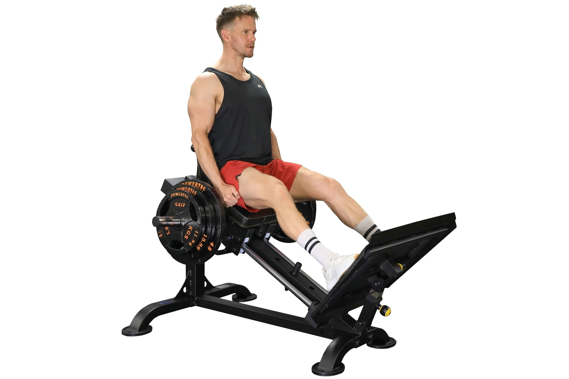 Man wearing black tank top and red shorts using Powertec black leg sled machine with weight plates, white socks, on white bac