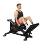 Man using black Powertec Leg Sled machine with weight plates, wearing black tank top and red shorts, on white background