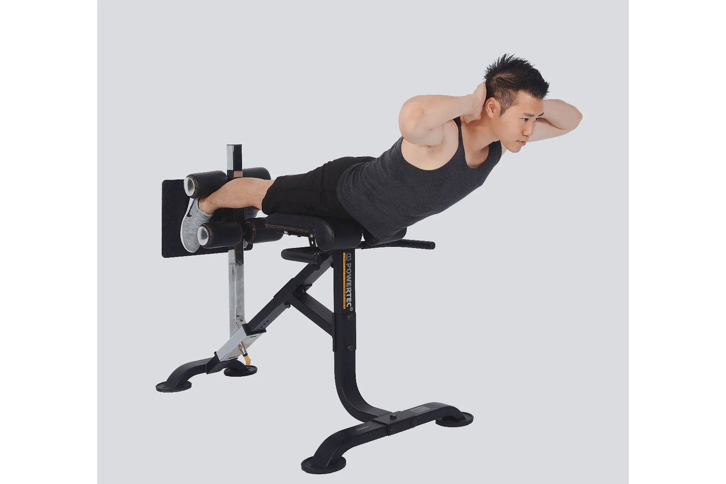 Man performing crunch exercise on black and silver Powertec dual hyperextension machine against white background