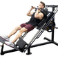 Man using black and silver leg press hack squat machine, wearing black tank top and maroon shorts, on white background
