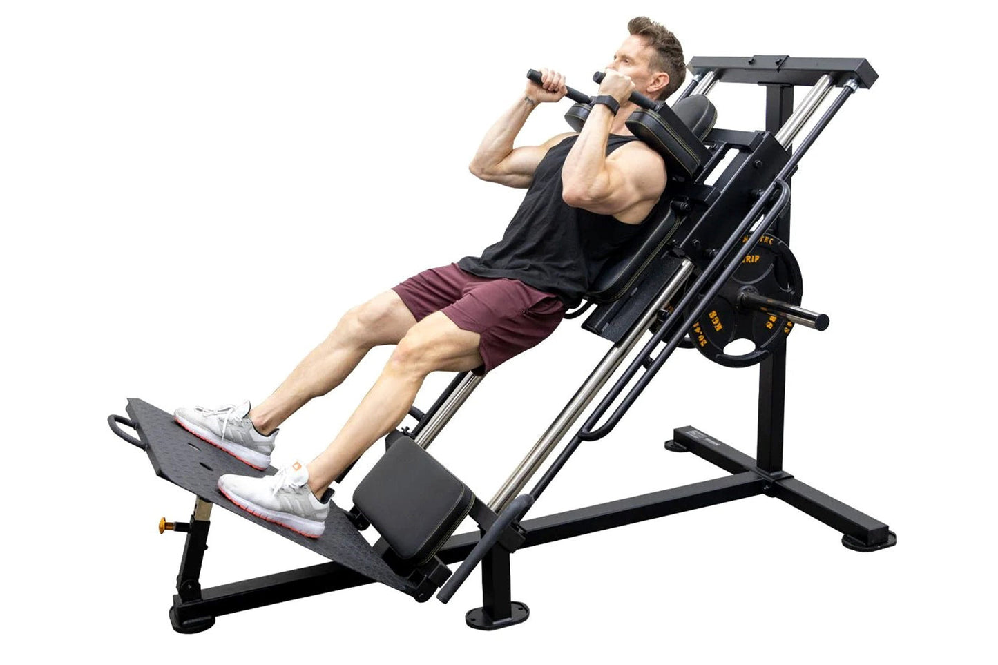 Man using black and silver leg press hack squat machine, wearing black tank top and maroon shorts, on white background