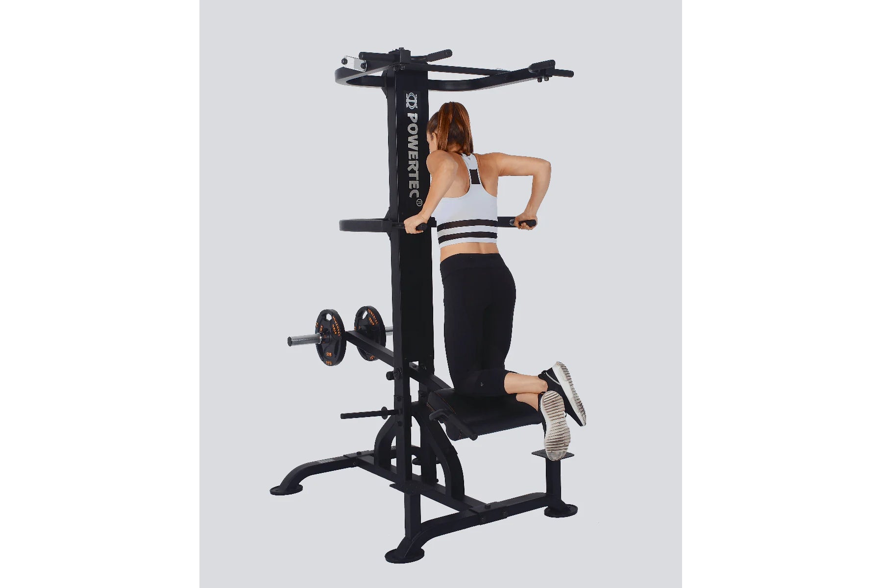 Black multi-station gym equipment with chin-dip assist, cable machine, and leg press, shown with model demonstrating use