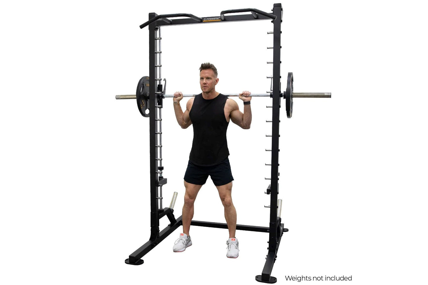 Black power rack with linear bearing smith machine system, man in black tank top and shorts performing barbell squat, white b