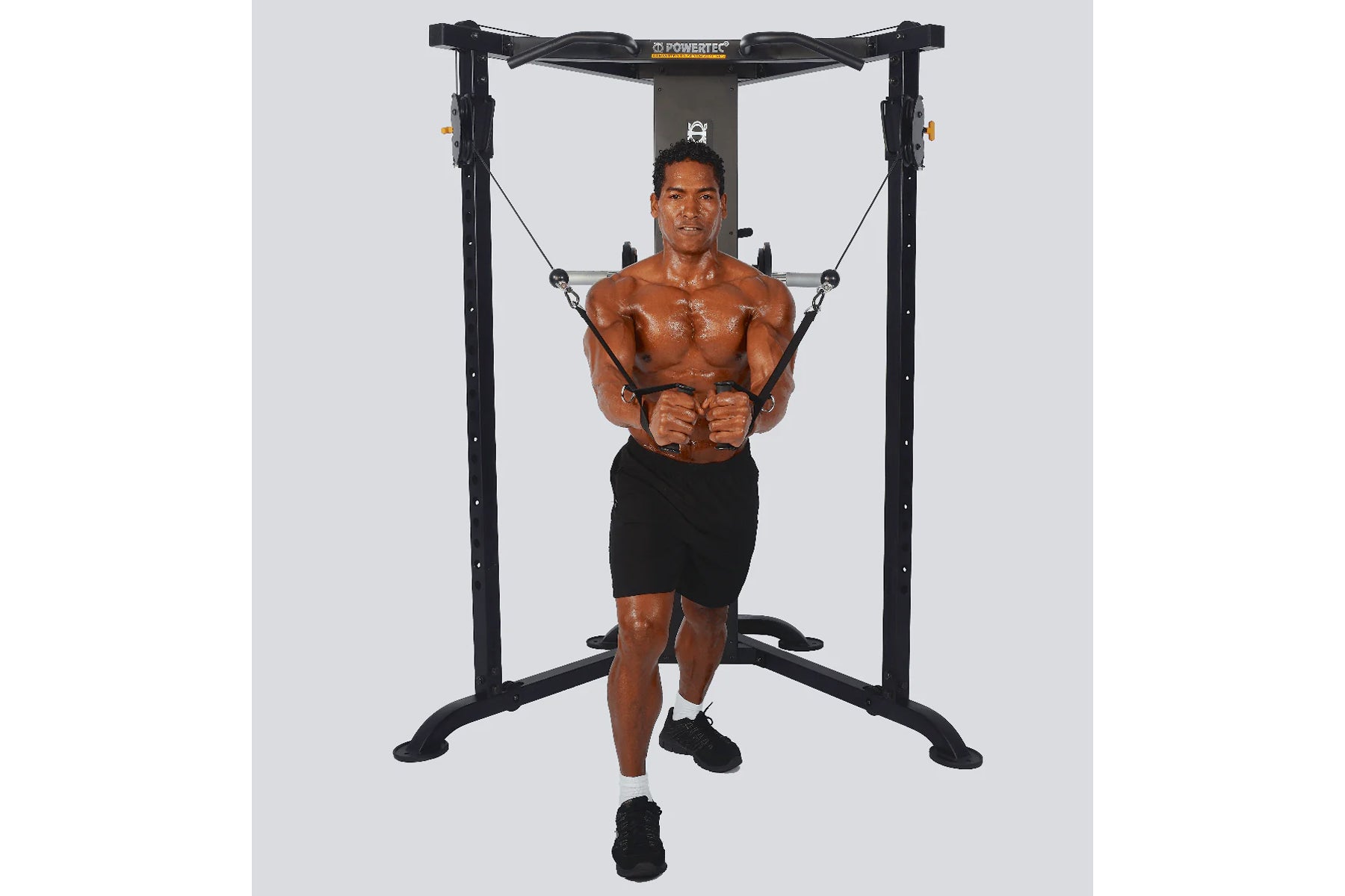 Powertec black functional trainer with dual cable stations, model demonstrated by shirtless man in black shorts performing ch