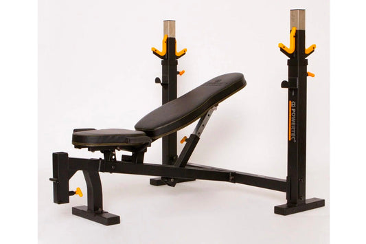 Black and yellow Olympic weight bench with dual squat racks and adjustable leg extension, on white background