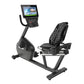 Black recumbent exercise bike with digital display console, ventilated seat back, and foot pedals on white background