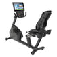 Black recumbent exercise bike with digital display console showing workout metrics and programs, ergonomic seat with ventilat