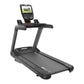 Black commercial treadmill with digital console display showing workout video, handrails, and running belt on white backgroun