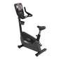 Black upright stationary exercise bike with digital touchscreen console, handlebar grips, and adjustable seat on white backgr