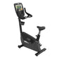 Black upright exercise bike with digital display console, handlebar, padded seat, and foot pedals on white background