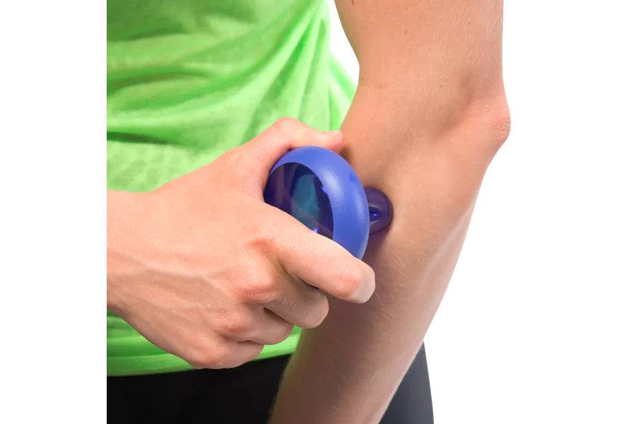 Blue handheld massage ball held in hand against arm, worn by model in green shirt