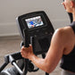 Person using ProForm Carbon E7 elliptical with black frame and interactive touchscreen display showing workout video