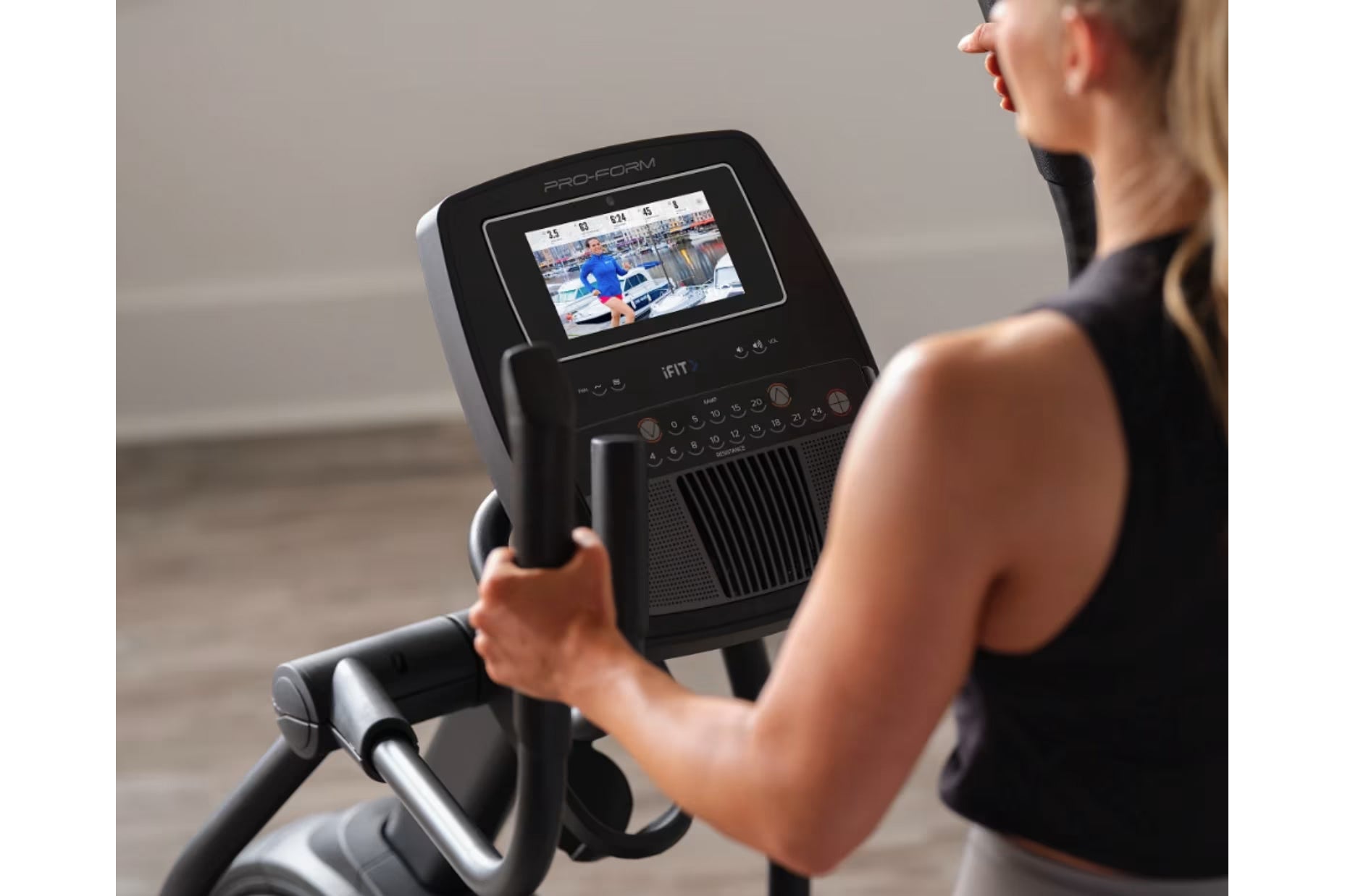 Person using ProForm Carbon E7 elliptical with black frame and interactive touchscreen display showing workout video