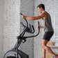 Man using black ProForm elliptical machine with digital console in modern loft-style bedroom with brick walls