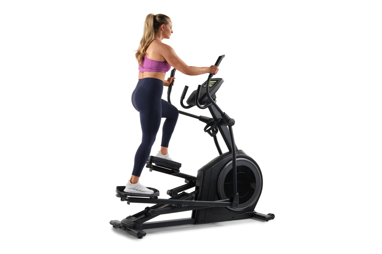 Woman in purple sports bra and navy leggings using black ProForm elliptical machine on white background