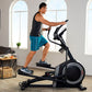 Man using black and gray elliptical machine with digital display in bright home gym with windows