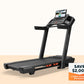 Black ProForm Carbon Pro 9000 treadmill with digital console displaying workout video, on beige background
