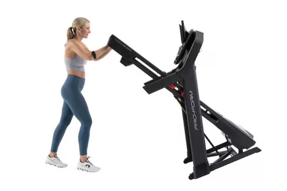 Woman in blue leggings and gray sports bra using black ProForm treadmill with digital display on white background