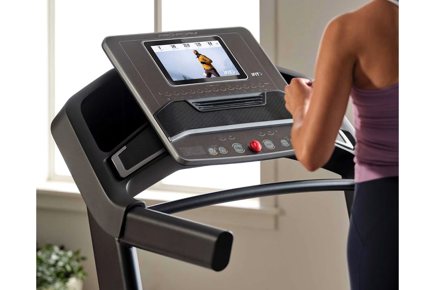 Black Proform treadmill with touchscreen display showing workout content, control buttons, and red emergency stop button, use