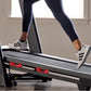 Person wearing navy leggings and white sneakers with black stripes running on ProForm Plus Trainer 1000 treadmill with red ha