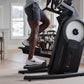 Person exercising on black ProForm elliptical machine with white wheel and handlebar in home gym setting