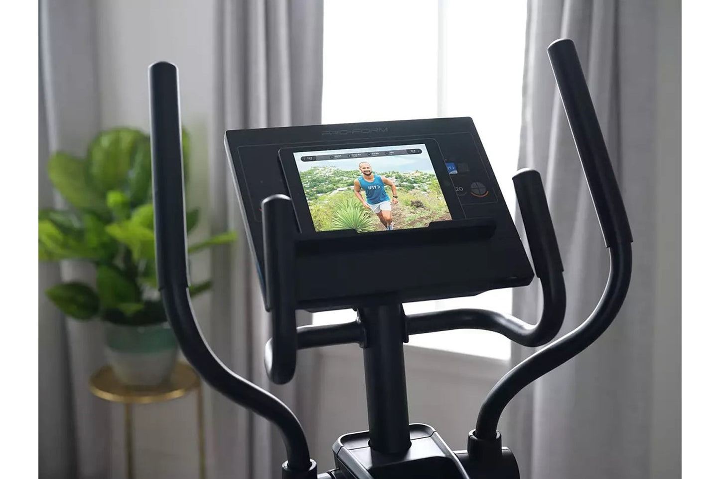 Black ProForm sport elliptical with digital display screen showing workout video, dual handlebar arms, and base positioned in