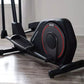 Black and red ProForm Sport elliptical machine with dual handles and foot pedals on wooden floor in home gym setting