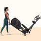 Woman wearing navy sports bra and teal leggings standing next to black ProForm elliptical machine with red accents on beige a