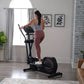 Woman wearing gray tank top and burgundy leggings using black ProForm Sport Elliptical in modern living room setting