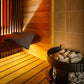 Harvia Spirit Safety Railing installed in wooden sauna interior with heated sauna stove and stones