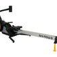 Shi-row air rowing machine with orange fan wheel, black seat, gray rail, and digital monitor on white background