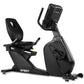 Black Spirit recumbent exercise bike with digital console display, padded seat and backrest, stationary on white background