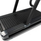Black sled treadmill with slat belt deck, upright handles, and metal foot plate on white background