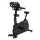 Black upright exercise bike with digital console, padded seat, handlebars, and foot pedals on white background