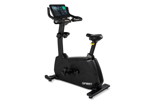 Spirit CU1000ENT black upright stationary exercise bike with digital display console and yellow handlebar accents, on white b