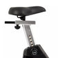 Upright stationary exercise bike with black padded saddle, gray metal frame with numbered adjustment holes, and black base wi