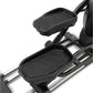 Black elliptical machine with textured foot pedals and upper body handles on silver frame, detail view