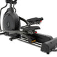 Black elliptical machine with large flywheel, adjustable footrests with red accents, and handlebars, on white background