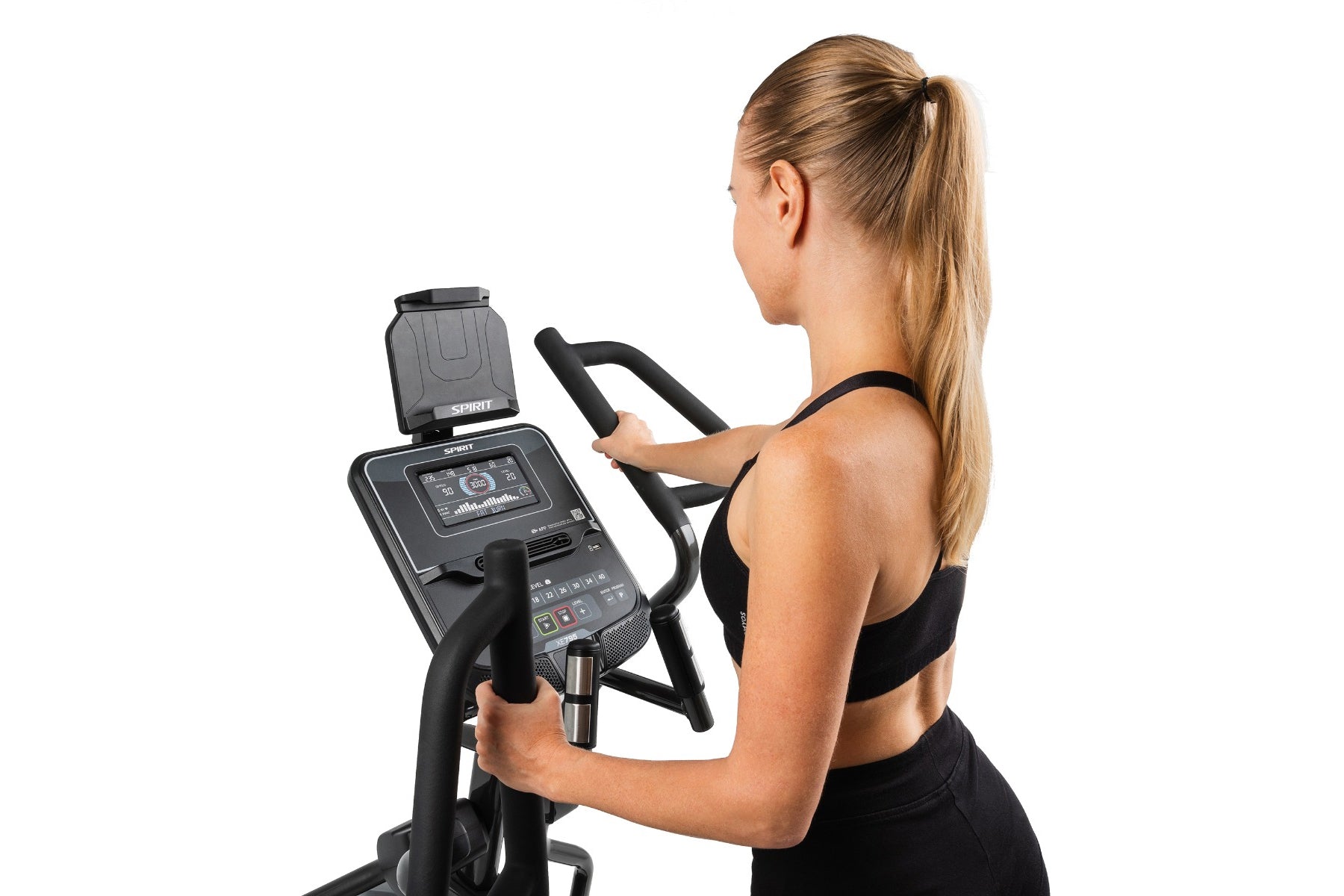 Woman using black Spirit XE795 elliptical machine with digital display, shown in side profile against white background